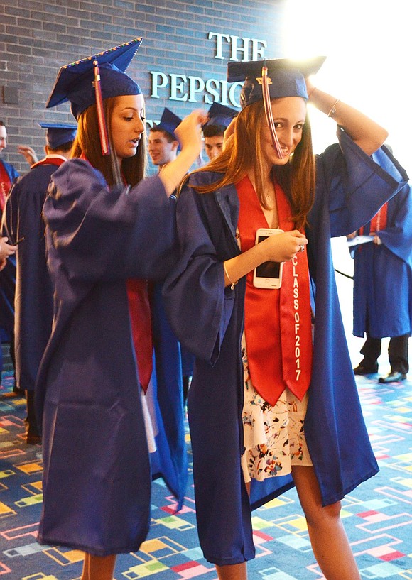 Allison Hamburger helps Katie Blinderman with her cap and gown before they take to the stage.