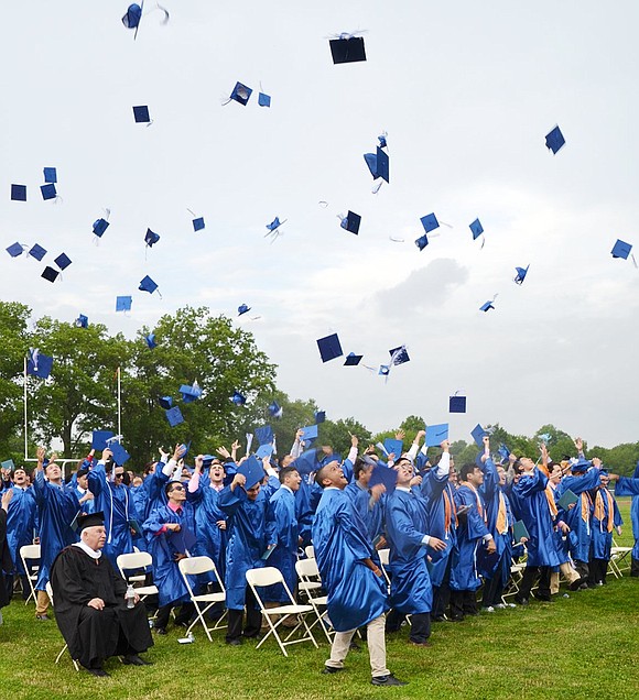 Boys throw their caps in the air after Principal Dr. Mitchell Combs declares them graduates.