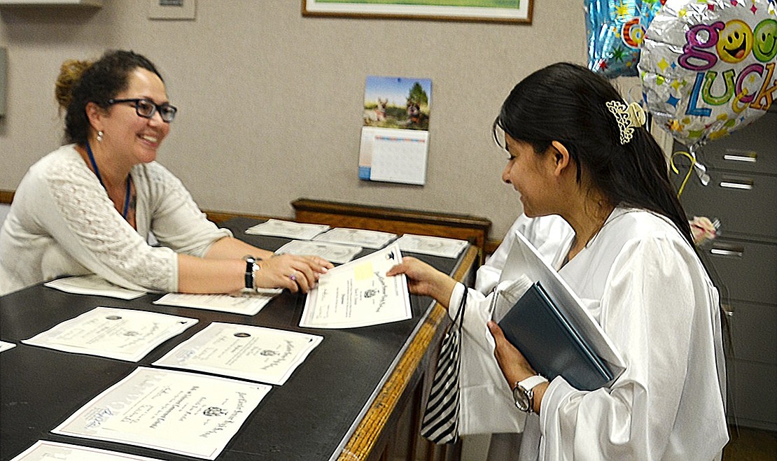 Graduate Keren Funegra picks up the diploma with her name on it in the main office after the ceremony.