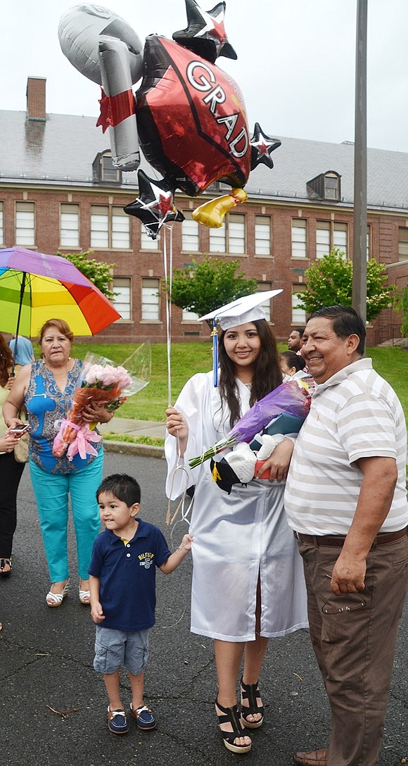 Graduate Melanie Pinto poses with her father George and 3-year-old nephew Herbert Delgado in the flag plaza after the ceremony.