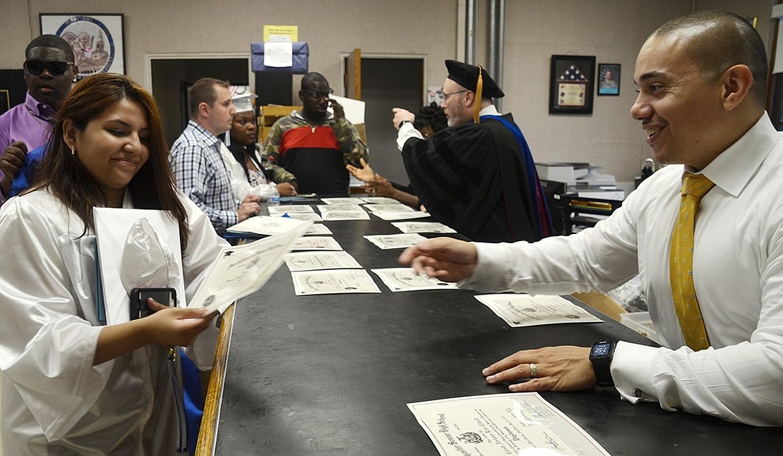 Graduate Valeria Palacios picks up the diploma with her name on it from Assistant Principal Juan Sanchez in the main office after the ceremony.