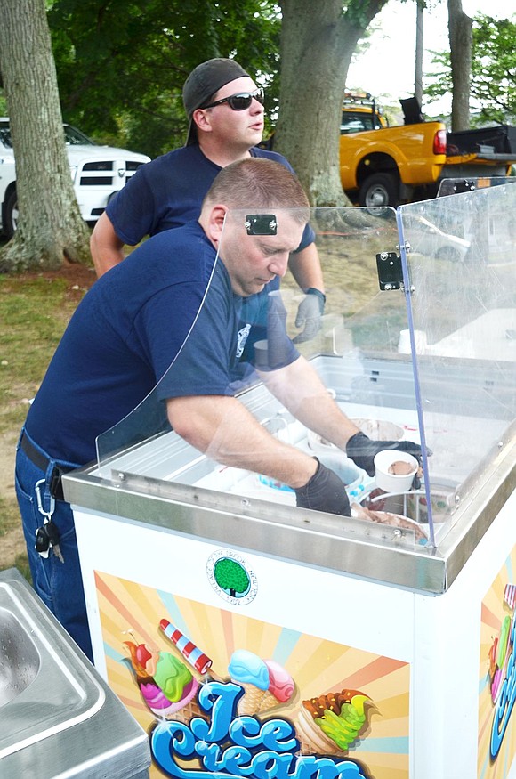 General Foreman of the Rye Brook Highway Department Paul Vinci and Joe Orlando of the village’s Parks and Recreation Office scoop ice cream to keep the long line of 40 people moving. 