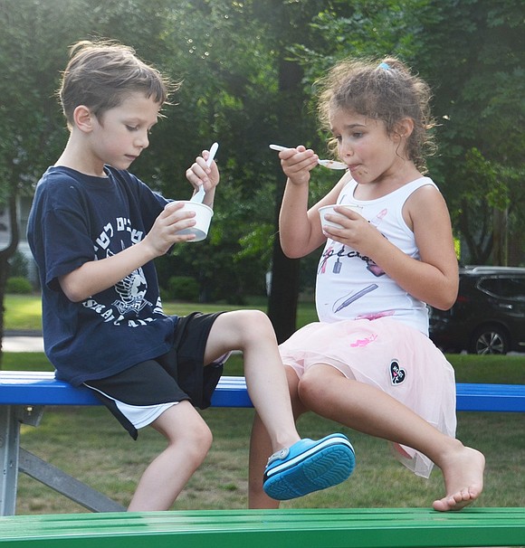 Six-year-olds Oleg Sidyelyev (North Ridge Street) and Gabrielle Sykes (Elm Hill Drive) share a bare-footed bite on a sweltering night. 