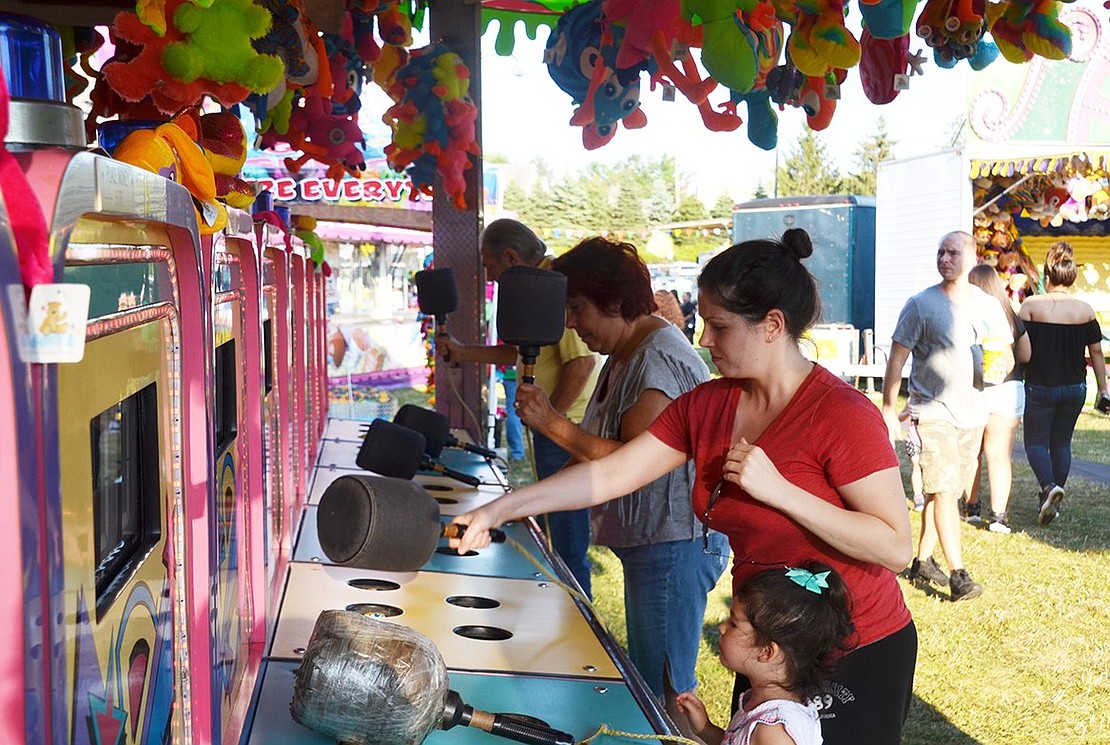 All ages can enjoy a rousing game of Whack-A-Mole. Jessica Gomez of Glen Avenue (front) challenges husband and wife duo Richard and Marianne Sorce of Woodland Avenue. 