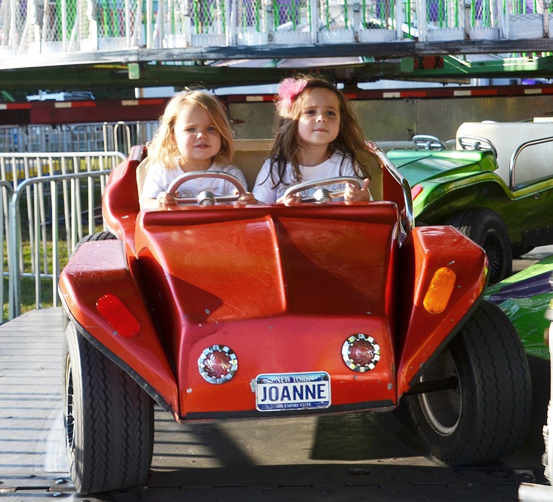 Indian Road residents and sisters Charlotte (left) and Emma Dunham try their hand at driving. The 4- and 6-year-olds’ attempt to move the ride off the rotating arm were unsuccessful. 