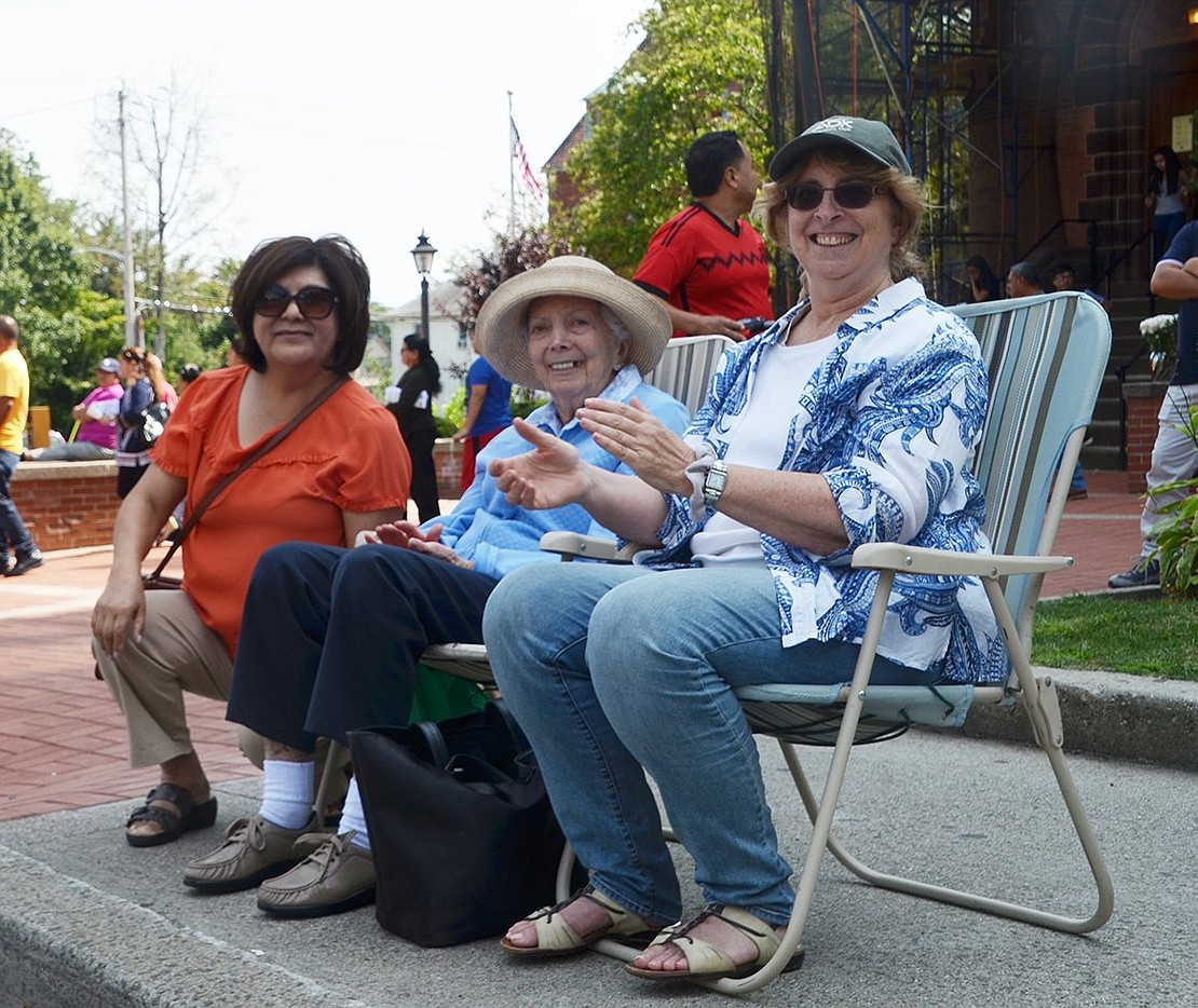 Lidia Vargas of Rye Brook (left), caregiver for Alberta Salkin of Rye (middle), and Alberta’s daughter, Leslie Millman of West Harrison (right), are among the throng of spectators watching the parade from in front of Our Lady of Mercy Church.