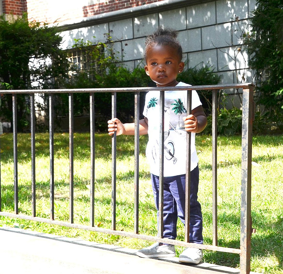 Two-year-old Saige Merritt of Westchester Avenue enjoys the parade behind the protection of the Port Chester Post Office fence. 