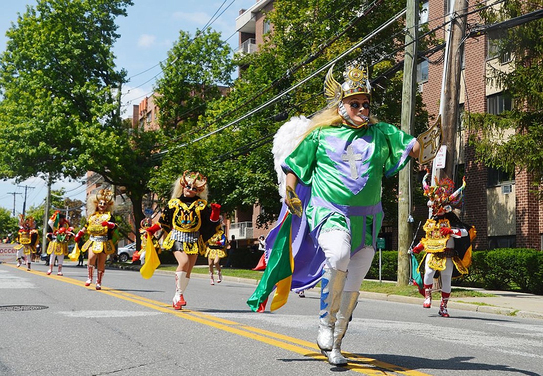 A procession of Fraternidad La Diablada (dancing devils) Port Chester is led by an angel. 