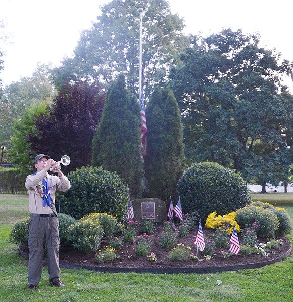 Port Chester High School senior William Brakewood, standing in front of the September 11 memorial, plays Taps.