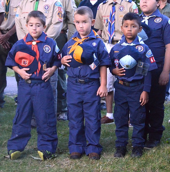 First grader Santo Giordano, second grader Evin Eski and third grader Dylan Loja, members of Cub Scout Pack 19, hold their hats over their heart while Gabriella Buccieri sings the National Anthem.