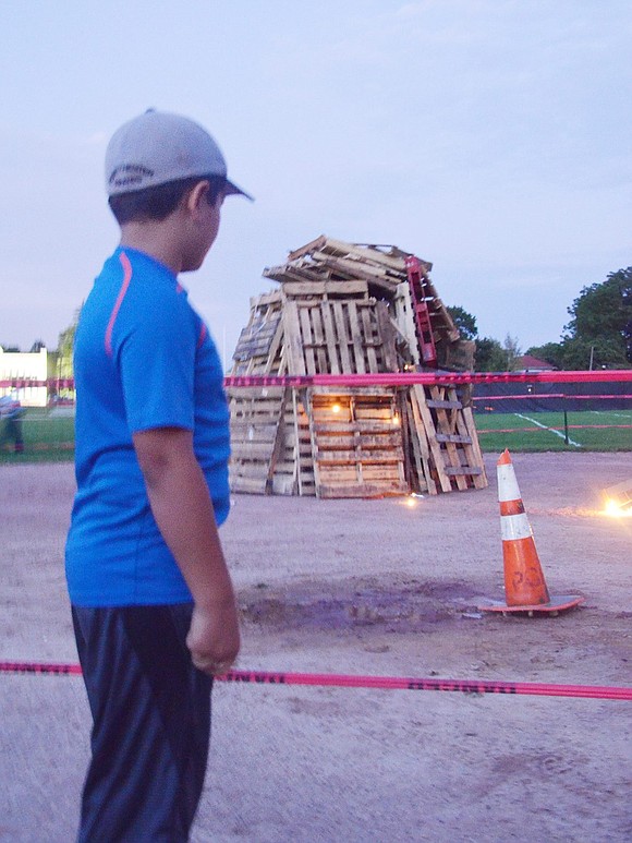 Fifth grader John Borzoni eagerly waits for the fire to take hold of the pallets during the Port Chester High School Bonfire and Pep Rally on Friday, Sept. 15. It took a few cup tosses of gasoline and extra flares, but the fire started quickly and captured everyone’s attention with a bright burst of blazing light. 