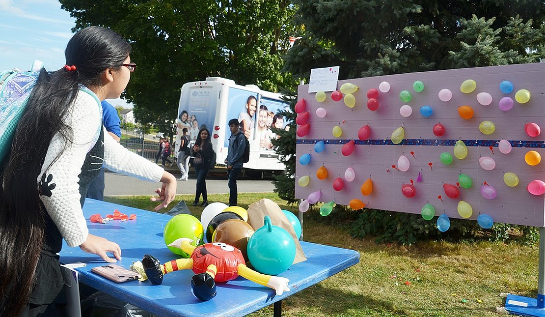 Freshman Nina Torres tries her aim as she throws darts at balloons. She popped one, but couldn’t land a second dart to win a prize. 