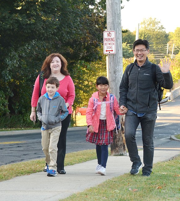 Give us a wave! Yinghao Wu (right) gives a happy wave as he, his 7-year-old daughter Melody, and friends John, 7, and Rosemarie Marciano arrive early to school. The second graders have known each other since preschool. 
