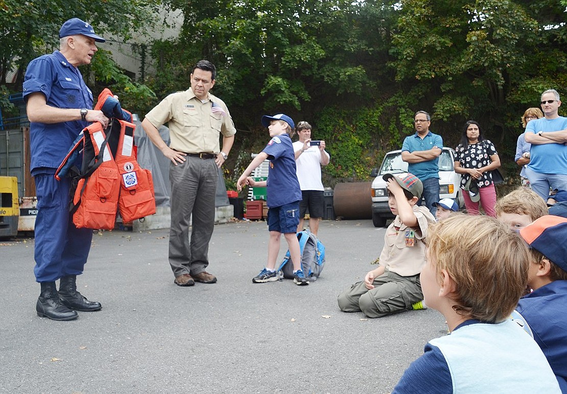 Coast Guard Auxiliary Lieutenant Mike Reidy shows Rye Brook Cub Scouts the equipment he commonly uses, such as life vests with reflectors. 