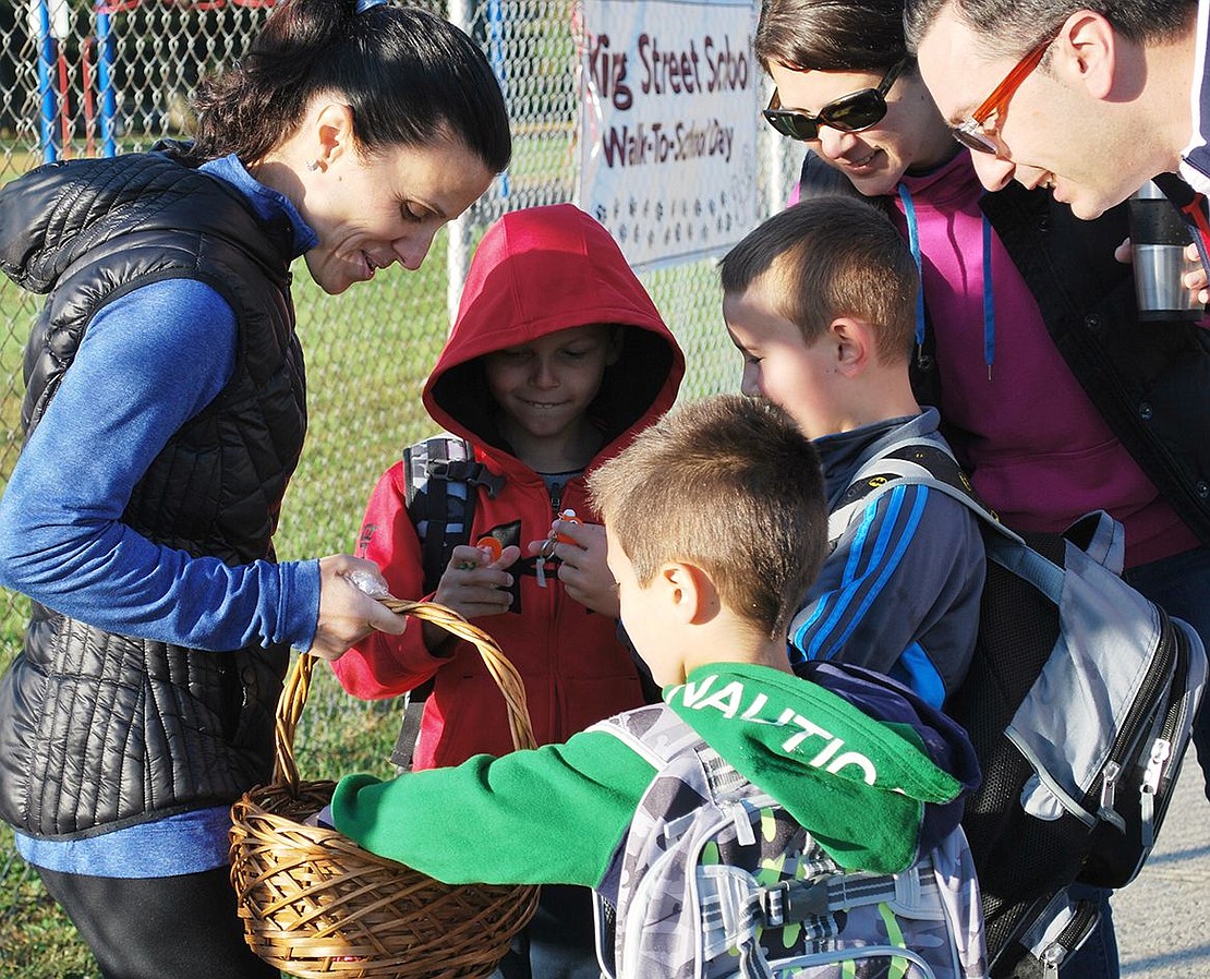 Students and parents gather around PTA parent Viviana Torregrossa to see what’s in her basket—goodies like magnets, pencils and toys she gave out to children who, in the spirit of the day, walked to school rather than getting a ride.