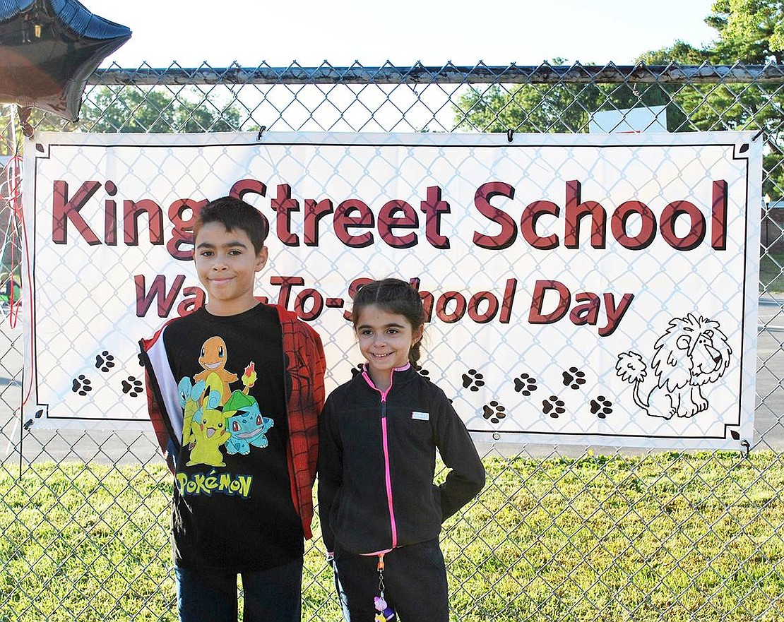 Fifth grader Lucas Faraci and second grader Sophia Faraci of Adams Avenue stand in front of the King Street School Walk to School Day sign hung on the fence on Upland Street.
