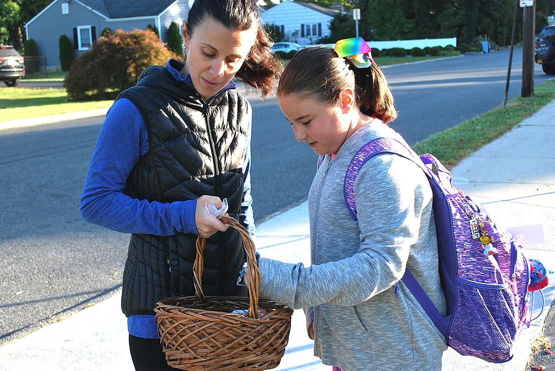 Fourth grader Ashley Krivinskas of Glen Avenue picks out a treat from PTA parent Viviana Torregrossa’s basket as a reward for walking.