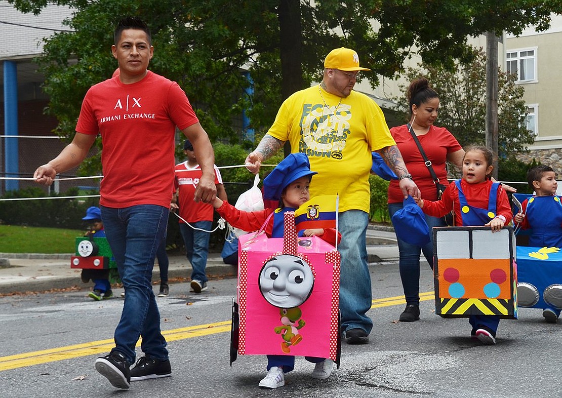 A train of preschoolers rolls down the street. Ashley Castillo, 4, was the brightest conductor, with a neon pink train engine, Yoshi sticker and Mario overalls. 