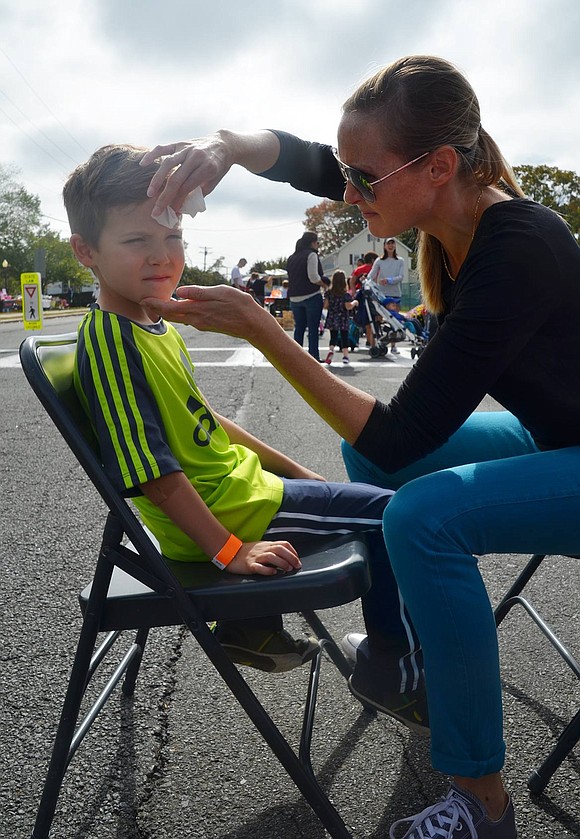 Six-year-old West Glen Avenue resident Emmett Vakil sits patiently as his mother Jessie Vogt fixes his snake face paint. 