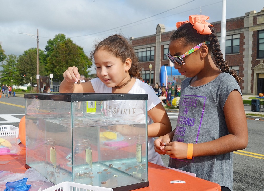 Port Chester 9-year-olds Sky Sams and Yvonne Santiago drop pennies into a tank, hoping they will land inside the “witches brew’ jar. 