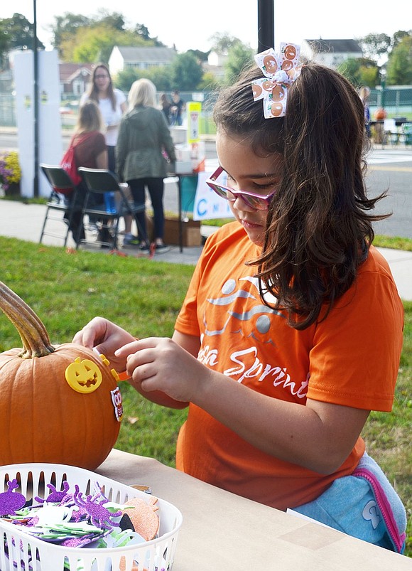 King Street School student Zoe Lopez decorates her pumpkin with stickers. The 7-year-old was among many students who were having a ball at Park Avenue School’s Harvest Festival on Saturday, Oct. 11. 