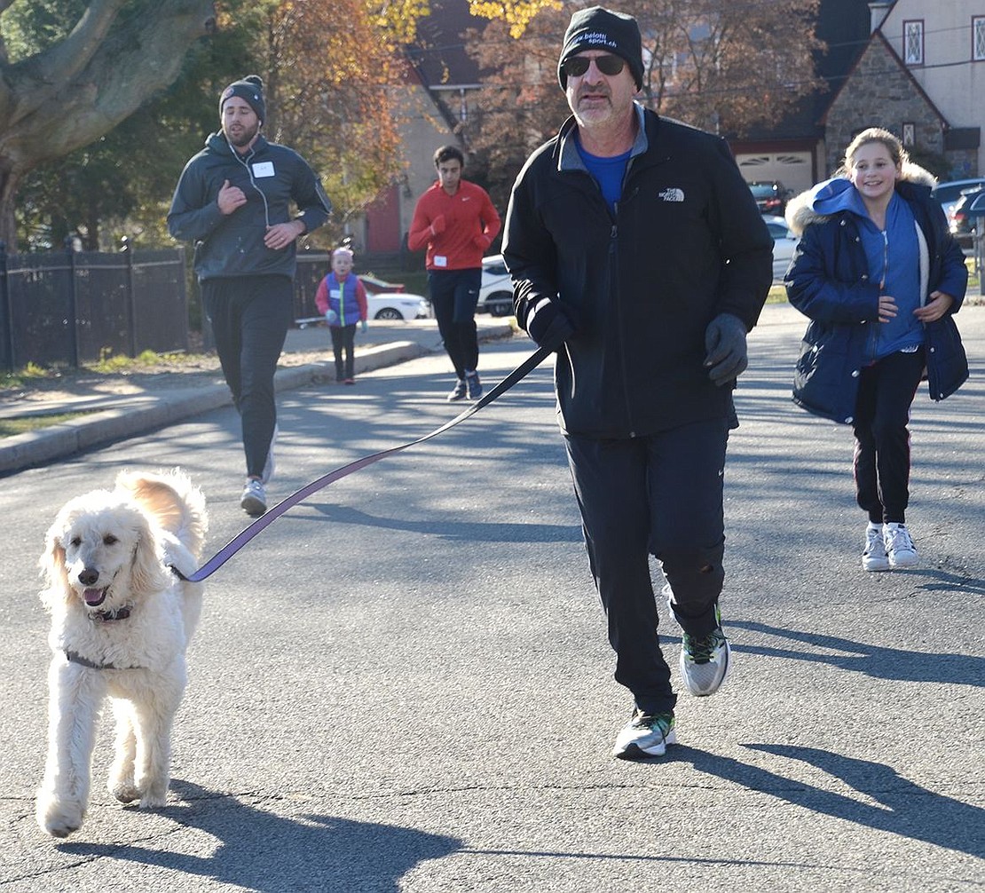 David Hartman of Argyle Road runs with his dog Scout, a Golden Doodle, in the Tamarack Tower Foundation Turkey Trot on Thanksgiving morning with runners of all ages behind him. David has been participating in the annual Turkey Trot, which starts and ends at the flagpole behind Port Chester High School, for several years.