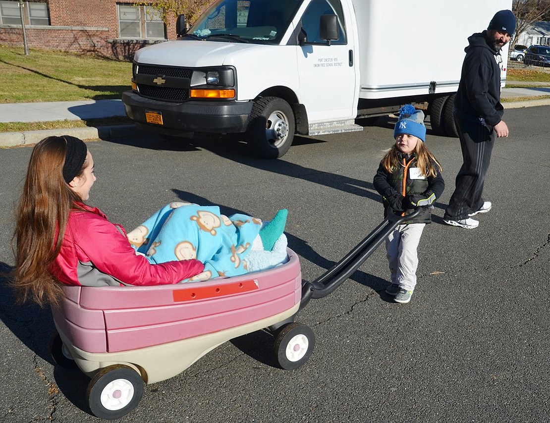 Three-year-old Derek Lovallo of Halstead Avenue pulls his cousin Francesca Sileo, 15, in a wagon before the walk/run because she had sprained her ankle while Derek’s father John looks on.