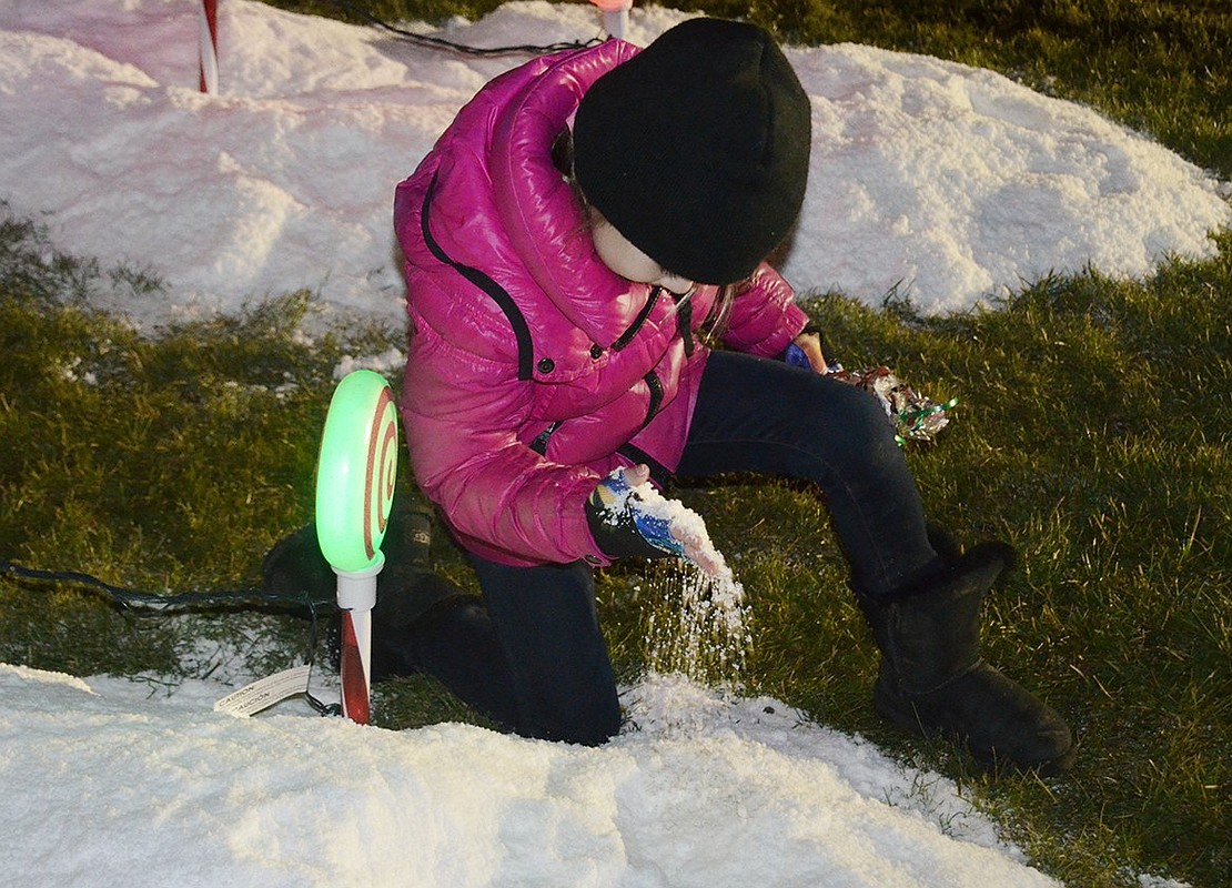 First-grade Ridge Street School student Hayden Sassower examines the fake snow outside the Santa booth at the festival.