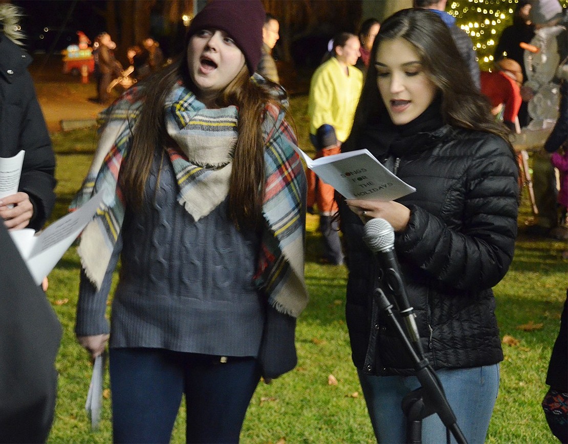 Kim Maguire (left), a 22-year-old South Regent Street resident, and 18-year-old Natalie Pugliatti of Rye sing holiday carols with a group from the Port Chester Council for the Arts. The organization provided a variety of entertainment pieces at Winterfest. 