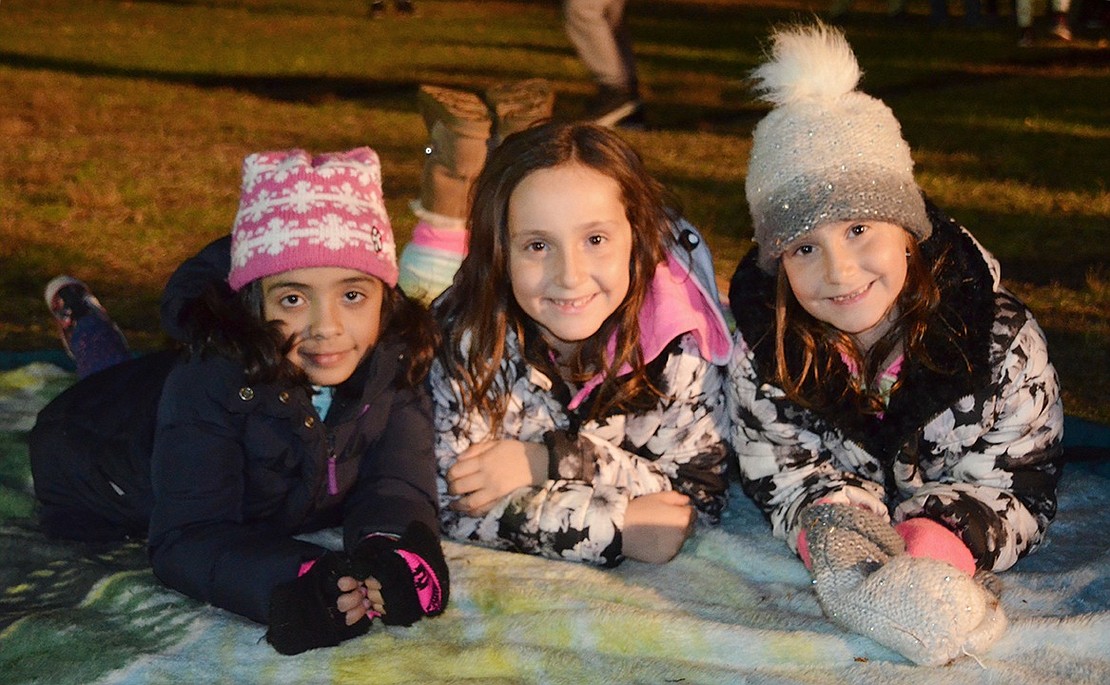 Madison Mollica (right) hangs out with twins Antonella Cabibbo and Francesca Cabibbo (left) at the park. The second-grade girls from Park Avenue Elementary School are lounging on a blanket while they wait in line with hundreds of others to meet Santa. 