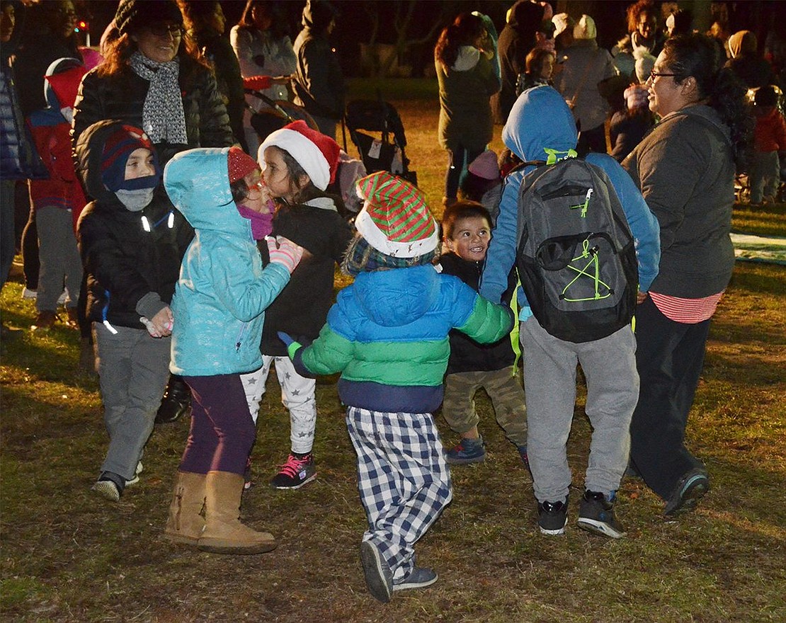 A group of kids decides to take a break from waiting in the long line to play Ring-Around-the-Rosie. 