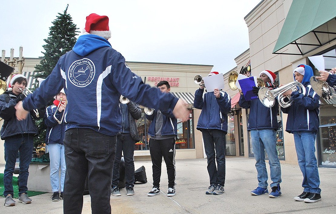 Santiago Bautista leads members of the Port Chester High School Marching Band brass section as they play holiday carols together in harmony at the Rye Ridge Shopping Center on Sunday, Dec. 3. The show kicked off a week-long Sportech promotion where the store donated a portion of its sales to the band. 