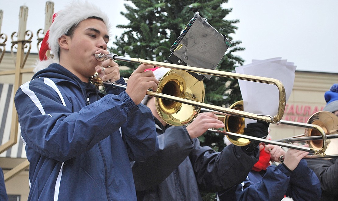 The drizzly weather doesn’t stop Brandon Molano from sliding his valve to playing carols on his trombone. 