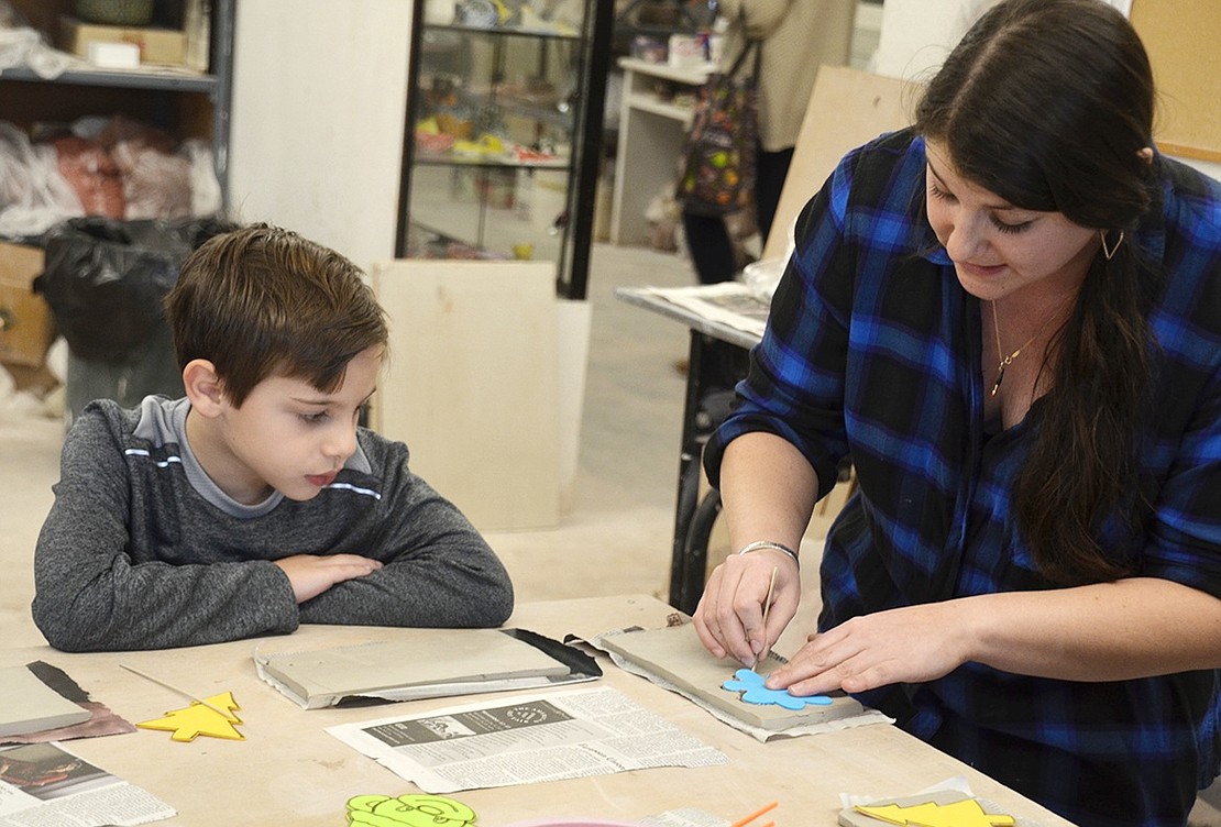 Luke Ciliberti, a 6-year-old from Thornwood, watches Zoey Scheler show the class how to cut out their ornaments. Scheler, the class instructor, is a 28-year-old resident artist at the Clay Art Center. 