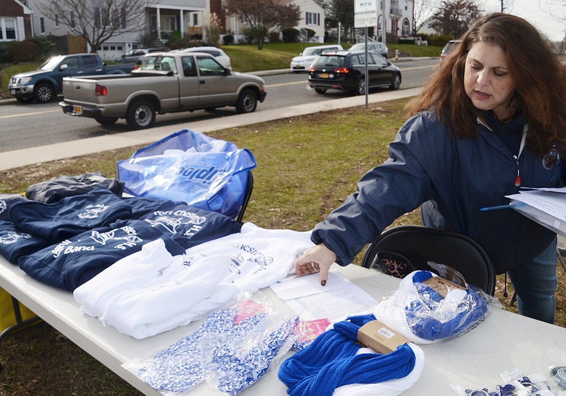 Debbie Scocchera, director of publicity for the Pride of Port Chester marching band, arranges merchandise for sale at the display table. 