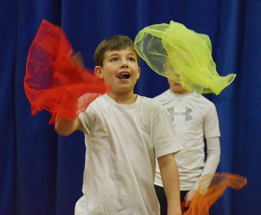 Tongue out and eyes on the prize, Chase Katz whips around some colorful cloth during the juggling act. 
