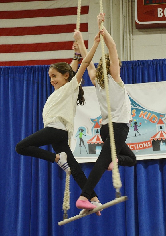 While the trapeze slowly rotates, Maddie Margolis (left) and Emma Yaches strike a sharp pose. 