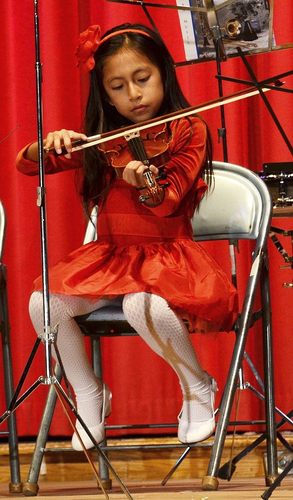Third-grader Ariana Ayala plays “God Rest Ye Merry Gentlemen” on the violin with the rest of the students in the string program at Corpus Christi-Holy Rosary School. 