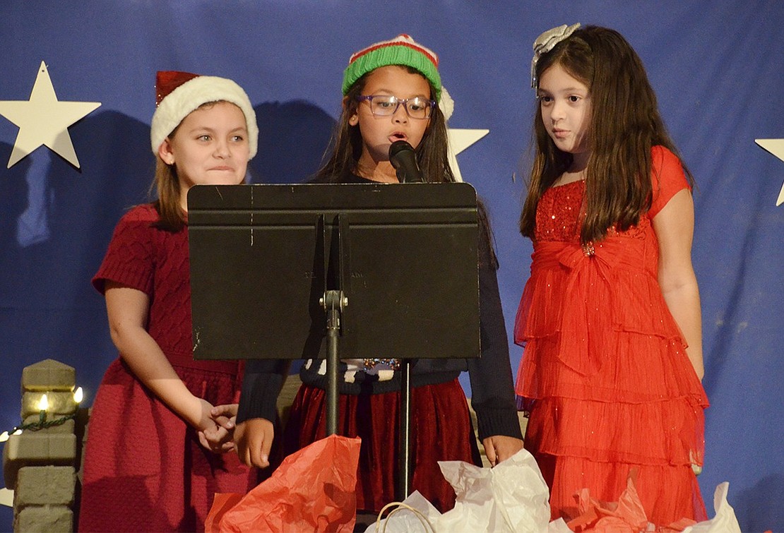 Christmas play between set entertainers Eliza DaSilva (left), Luna Silva and Gianna Marriott set up the kindergarteners’ act and entertain the audience with jokes about holiday shopping madness. 