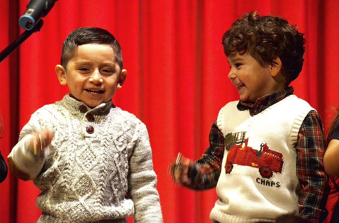 Arkgel Duchimaza (left) and Lucas Pedreyra, three-year-olds at Corpus Christi-Holy Rosary, giggle and eagerly wiggle their bells while singing “Jingle Bells.” 