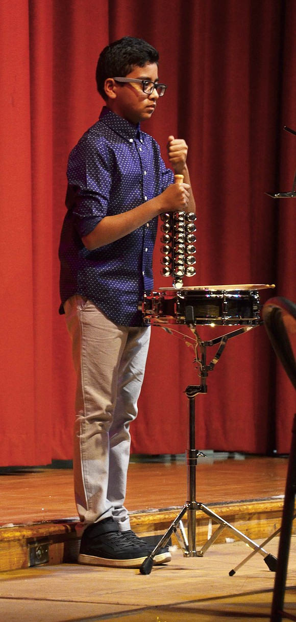 Michael Pace, a sixth-grader, sets the beat for the band students while mimicking sleigh bells as they play “A Christmas Sleigh Ride” at the concert. 