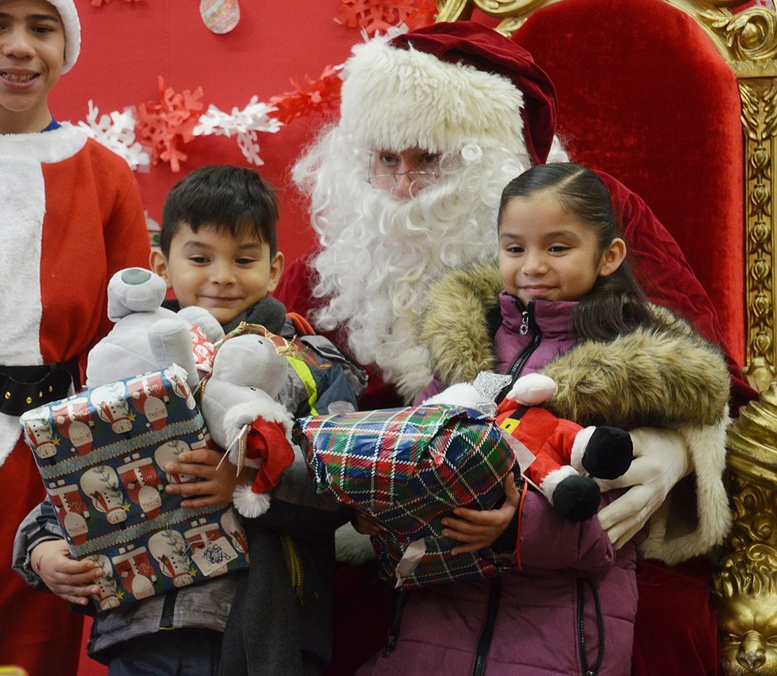 John F. Kennedy Elementary School siblings 6-year-old Aylee Pantoja and 5-year-old Axel Pantoja are happy to meet Santa, also known as longtime member of the Holy Rosary parish Nick Mecca, during the annual Santa Saturday at the Don Bosco Center gymnasium on Saturday, Dec. 16
