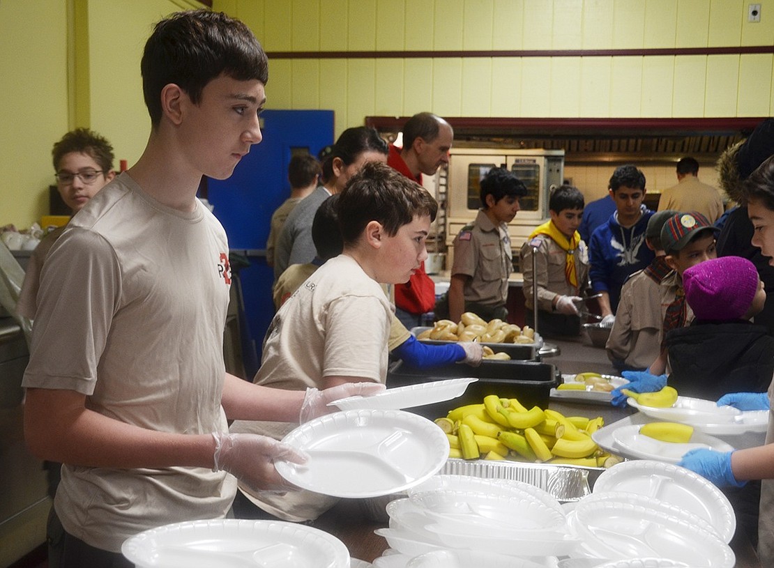 Austin Harvey, a 14-year-old Rye resident with Cub Scout Pack 2, is at the start of the food serving line passing out plates to the community lining up for breakfast. Multiple Cub Scout packs from Port Chester, Rye and Greenwich, Conn. volunteered for Santa Saturday and were in charge of organizing, cooking and serving breakfast for 1,300 families.