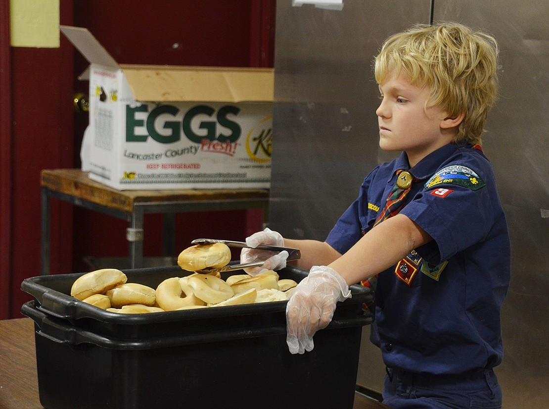 Grayson Brehm, a 9-year-old Greenwich resident with Pack 9, is ready to serve bagels in the breakfast line. 