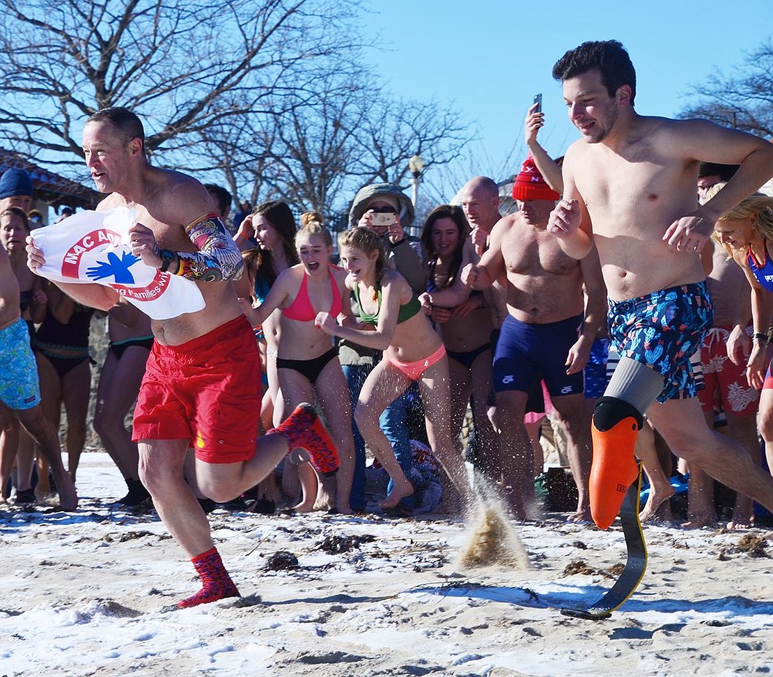 Bearing the MAC Angels Foundation logo and shouting “Freedom,” Phil Gormley, a Polar Plunge establisher, leads the crowd of participants into Long Island Sound during the 16th Annual Ray’s Polar Bear Plunge at Oakland Beach at Rye Town Park on Monday, Jan. 1.          