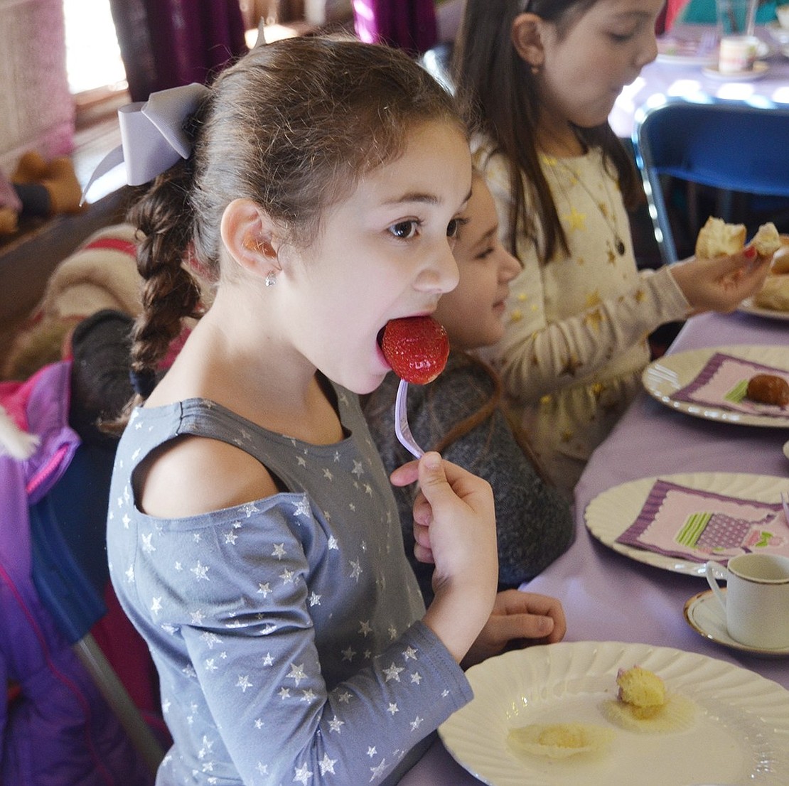King Street School 6-year-old Juliet Petriello takes a big bite out of a giant strawberry during brunch. 