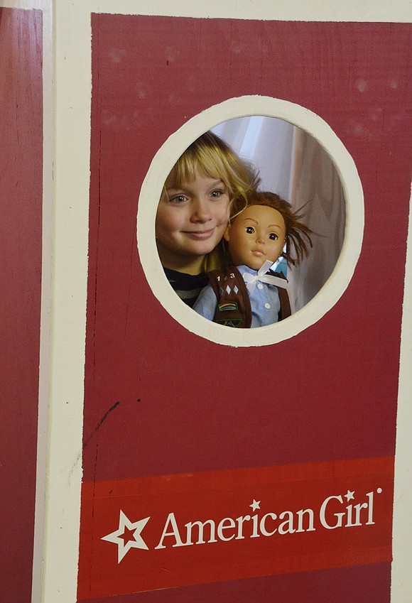 Cassandra Andrusco, a 7-year-old Yonkers resident, poses with her doll inside the American Girl doll photo booth. 