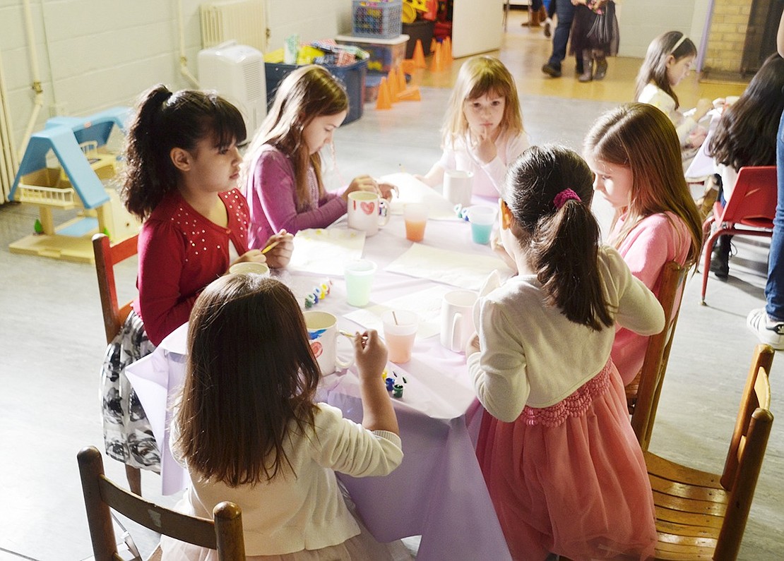 A group of Port Chester Girl Scouts from various troops paint mugs together at a craft table in the basement of the Girl Scout House at Lyon Park.  