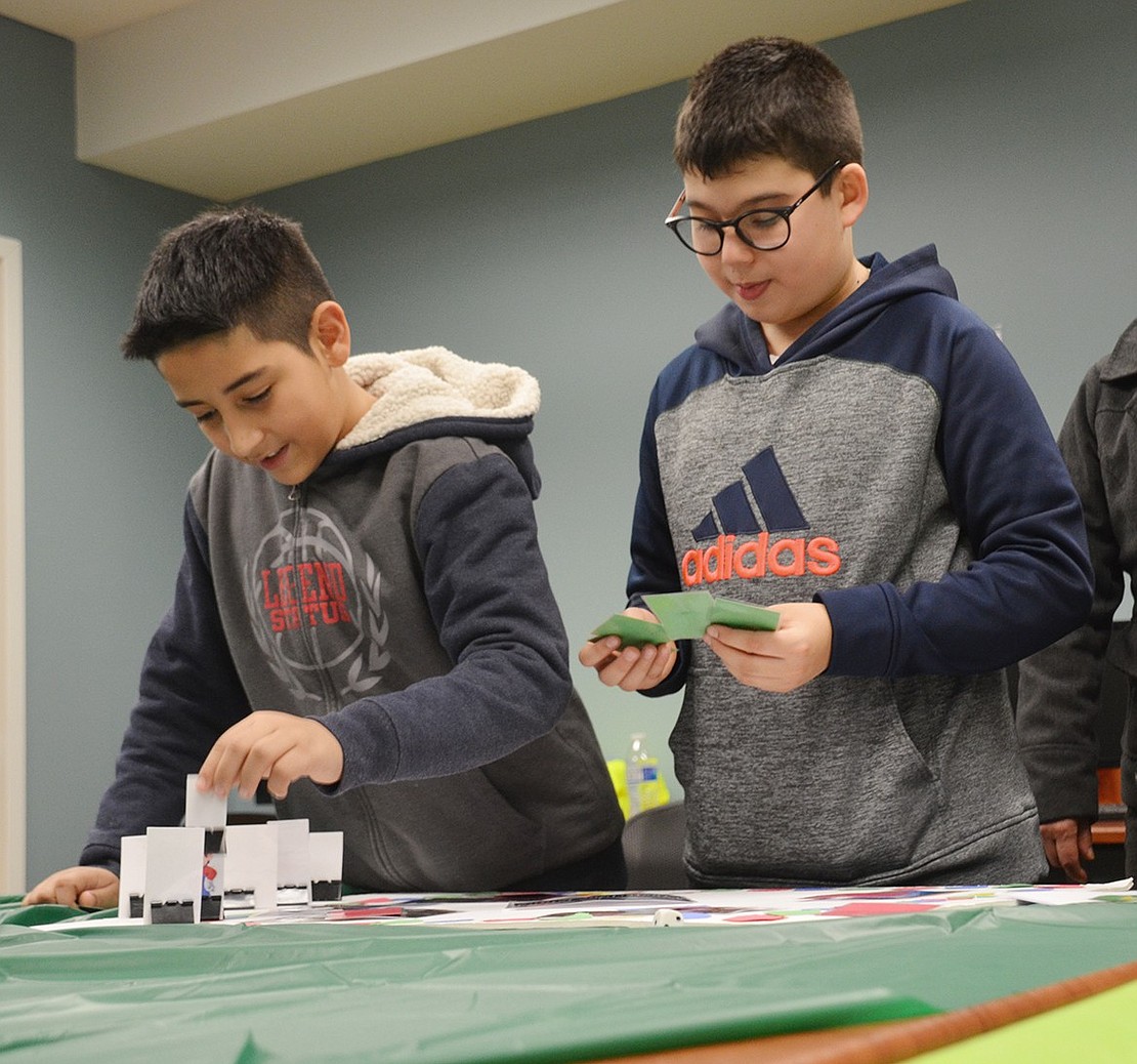 Port Chester Middle School 11-year-olds Giovanni Oliveros (left) and Sebastian Sabillon play a board game they made together “from scratch” in the gamer design program. 