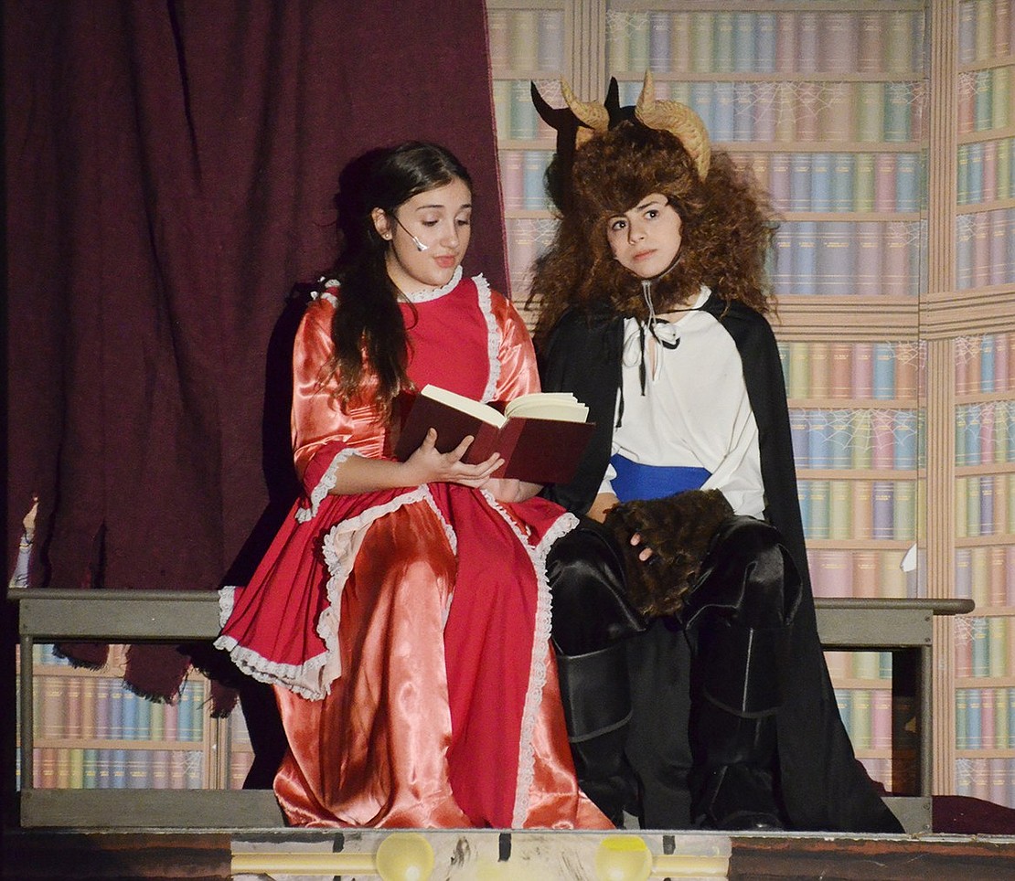 After being gifted her new library, Belle, played by Gwen Dominguez, and the Beast, played by Michael Perrone, bond while reading King Arthur. 
